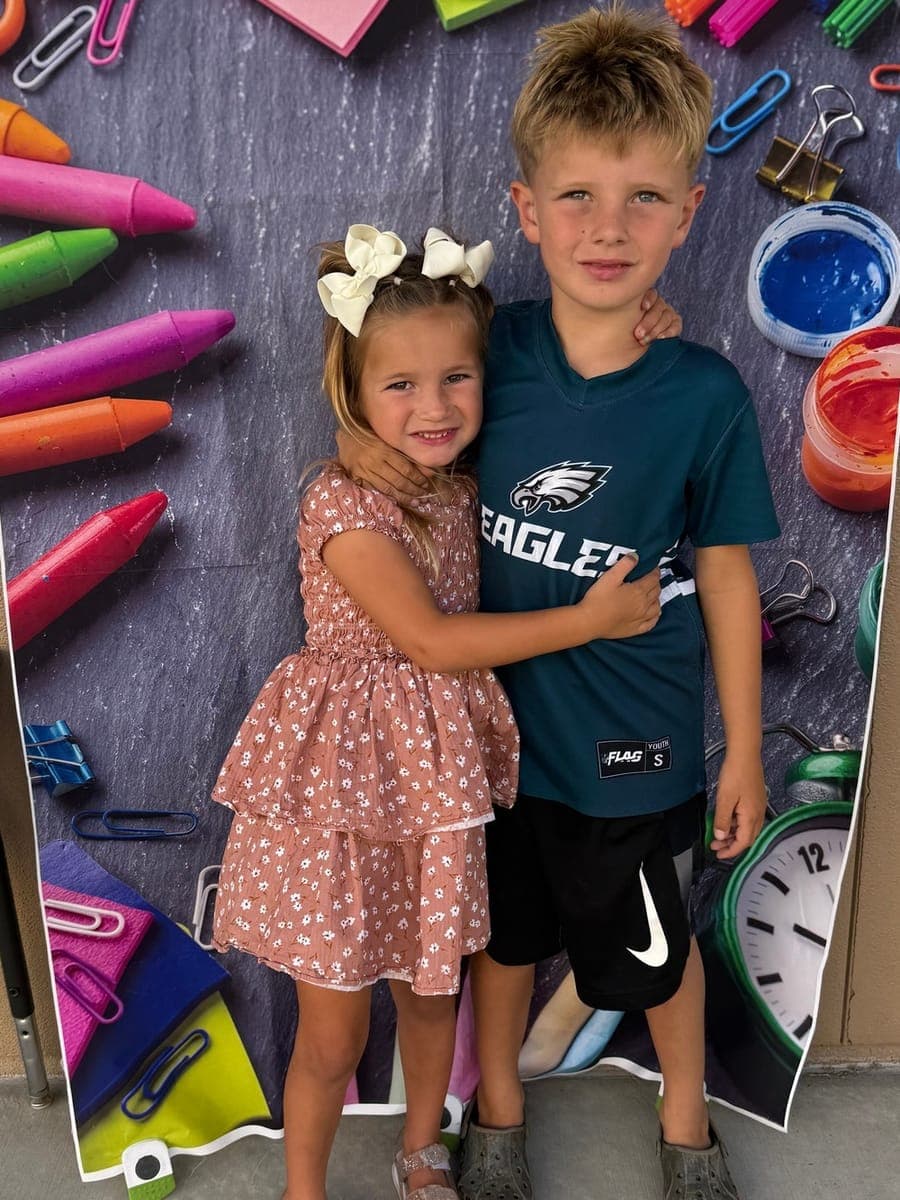 The photo the family sent: Lucy, in a pink floral dress with cream bows in her hair, hugging her older brother Beau, who has short blond hair.